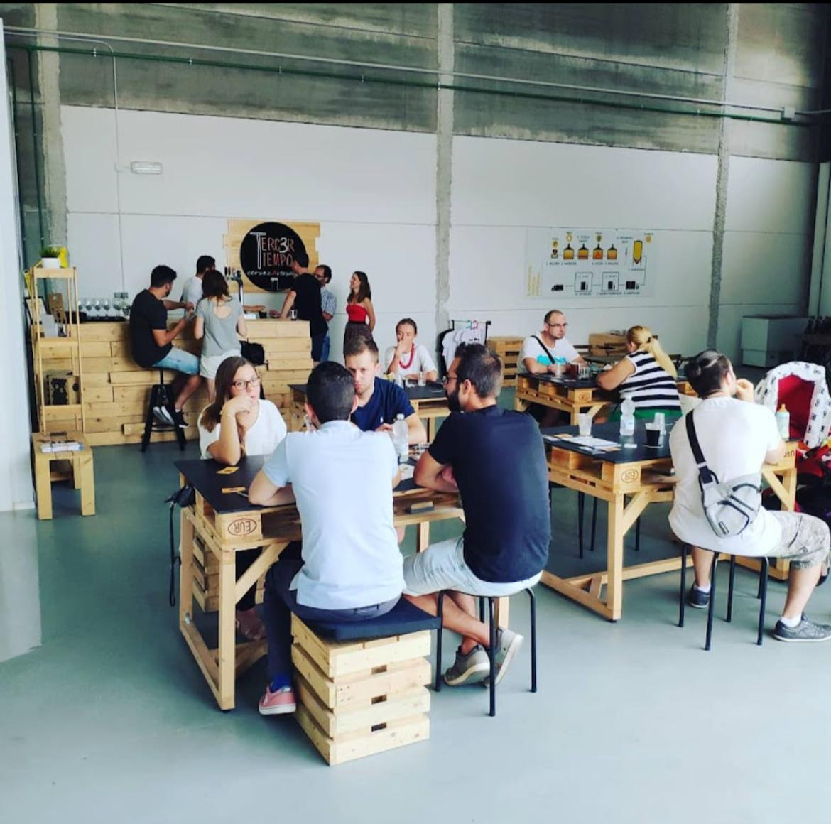 Taproom de Tercer Tiempo en La Pobla de Vallbona: mesas de palet y gente compartiendo cerveza